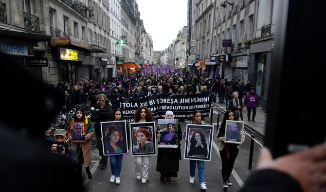 Des manifestants tiennent les portraits des victimes de la fusillade de la rue d'Enghien à Paris le 23 décembre 2022, et ceux des meurtres de la rue La Fayette en 2013, alors qu'ils participent à une marche pour leur rendre hommage et en solidarité avec la communauté kurde de Paris le 26 décembre 2022. (Photo, AFP)