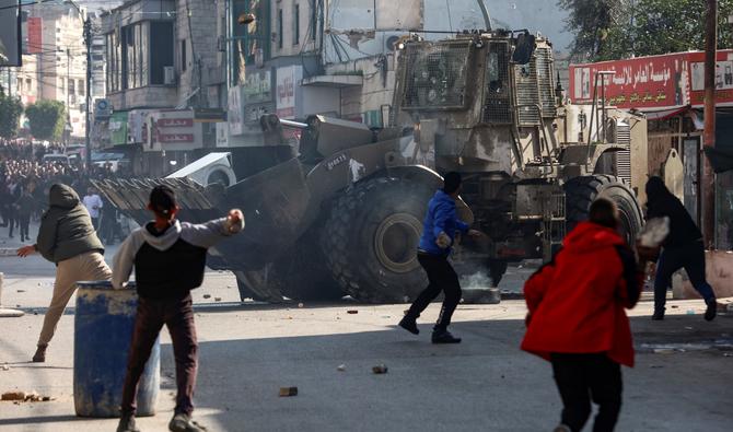 Des Palestiniens lancent des pierres sur un bulldozer de l'armée israélienne, lors d'affrontements dans la ville de Jénine, en Cisjordanie occupée, le 26 janvier 2023. (AFP)