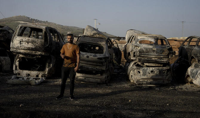 Un Palestinien fume devant des voitures incendiées lors d’une attaque de colons à Hawara, près de la ville de Naplouse en Cisjordanie (Photo, AP).
