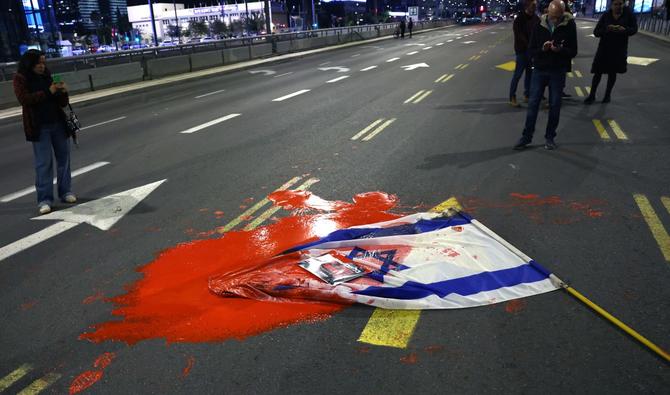 Un drapeau israélien est recouvert de peinture rouge alors que des parents et des sympathisants d'otages détenus par des militants palestiniens manifestent devant le ministère israélien de la Défense à Tel Aviv, le 15 décembre 2023. (Photo par Ahmad Gharabli AFP)