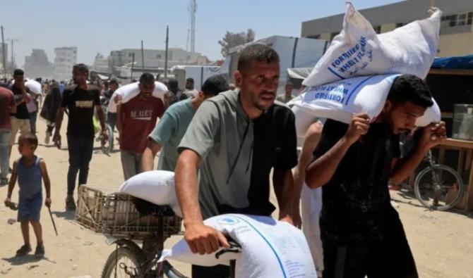 Des Palestiniens transportent des sacs de farine alors qu'ils se rassemblent pour recevoir de l'aide à Khan Younis, dans le sud de la bande de Gaza, le 26 juin 2025. (Reuters)